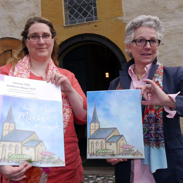 Kantorin Angelika Riegel (links) und Kunstmalerin Maren Sagemüller laden mit dem neuen Plakatmotiv zur Konzertreihe „Eine Kleine Marktmusik“ in die Stadtkirche Rheda ein.